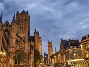 An illuminated gothic cathedral and towers in a historic city at night, historic buildings with