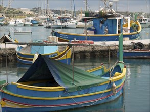 Various fishing boats are moored in the harbour, standing in calm waters, many colourful fishing