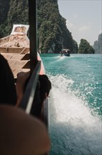 View over a passenger's shoulder of the sea and rocky cliffs. Khao Sok National Park, Thailand,