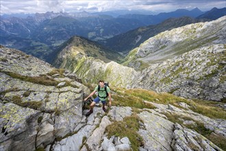 Climber on a steel cable secured path, view of mountain panorama with Lesachtal valley, ascent to