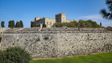 View of a castle across a large stone fortress wall, against a blue sky, Grand Master's Palace,