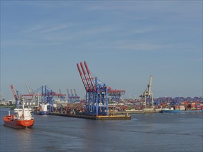 Container harbour with large cranes and ships in the water under blue sky, cranes and ships in a