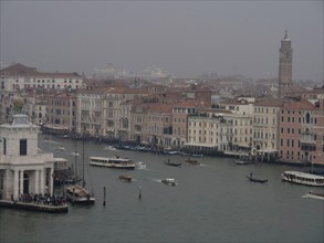 Venetian canal with historic buildings and boats in a foggy atmosphere, church towers and historic