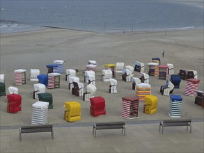 Many colourful beach chairs on the beach, the sea in the background and a cloudy sky, beach chairs