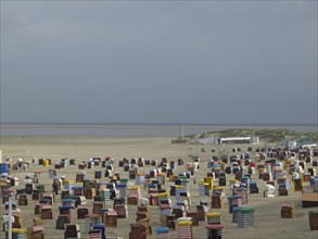 Numerous colourful beach chairs are located in large numbers on the empty beach with a wide view of