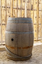 Old large wooden barrel on the street in front of a wooden door
