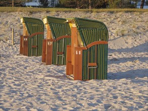 Row of beach chairs on the beach in front of a pier below waving flags on a sunny day, beach chairs
