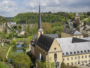 Panorama of a city with a church and a river, surrounded by historical buildings and green hilly