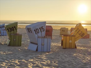 Colourful beach chairs on the sand while the sun goes down, sunset on a quiet beach with many
