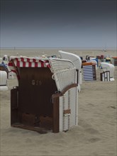 A single beach chair stands on a deserted beach under a cloudy sky, beach chairs and beach tents by