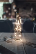 A light bulb in a bottle on a table creates a cosy atmosphere. Koblenz, Germany, Europe