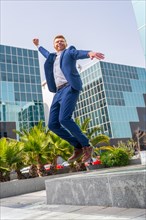 Vertical photo of a happy businessman jumping next to financial building