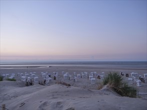 View of beach chairs on the beach with pastel coloured sky and calm atmosphere, setting sun on a