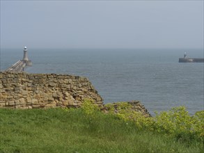 Ruins on the coast with a lighthouse stretching into the sea, ruins and old stone walls by the sea,