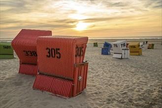 Several beach chairs on the beach at sunset, focus on red baskets, many colourful beach chairs on a