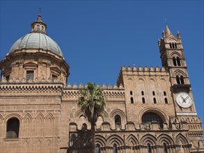 Side view of a historic cathedral with a striking dome and a clock on the tower, against a blue