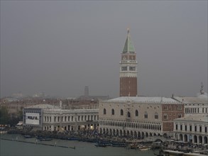Campanile of Venice, surrounded by historic buildings, in a misty evening mood, church towers and