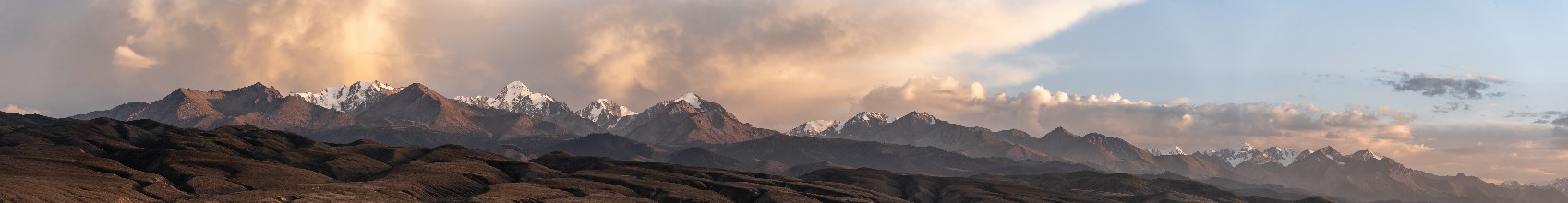 Snow-covered and glaciated mountain peaks at sunset, autumnal hills with brown grass, Issyk Kul,