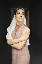Portrait of ballerina in beige dress hugging herself on black background