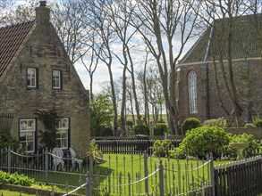 House with garden, chairs and table, in the background a church in the sunlight, historic houses on