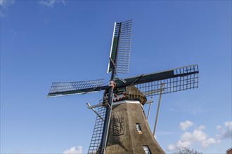 Historic windmill in front of a clear blue sky on a sunny day, windmill with a fence in front of