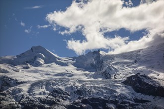 Towering snowy mountains and glaciers under a sky with few clouds, snow on high mountains in the