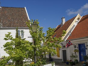 White houses with red tiled roof and norwegian flag, sunny day with blue sky, white wooden houses