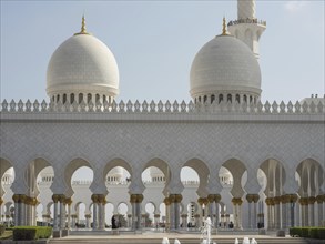 Gleaming white mosque with elegant domes and arches on a clear day, beautiful mosque with white