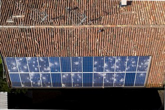 Direct overhead view of a roof with terracotta tiles and damaged solar panels casting shadows