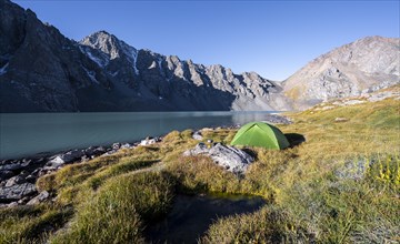 Mountain landscape at the turquoise Ala Kul mountain lake, green tent camping in the mountains,