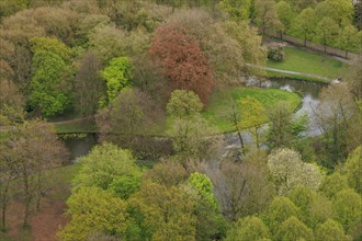 An idyllic park picture with a river surrounded by lush green vegetation and trees in spring mood,
