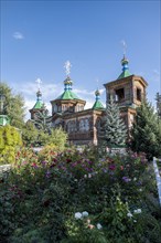 Flowers in front of the Russian Orthodox Church Cathedral of the Holy Trinity, wooden church with