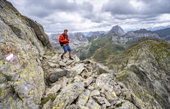 Mountaineer on a narrow rocky mountain path on a ridge, descent from the Raudenspitze, view into