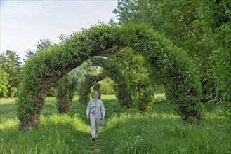 Woman goes for a walk, Topiary Garden, Symphonic Willow Walk, Boizenburg, Mecklenburg-Vorpommern,