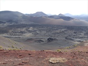 Extensive volcanic landscape with hills and rocks under a cloudy sky, barren landscape with roads,