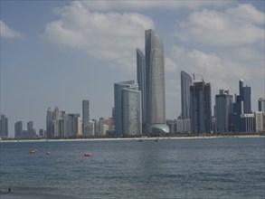 A city with modern skyscrapers by the sea under a slightly cloudy sky, impressive skyline of a