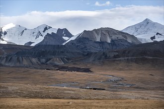 Autumnal plateau with brown grass, glaciated and snow-covered peaks, Ak Shyrak Mountains, near the