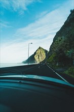 View from the car on a coastal road along steep cliffs with sea view... Madeira Portugal