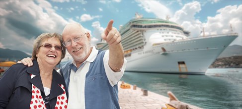 Senior couple on shore in front of cruise ship while on vacation