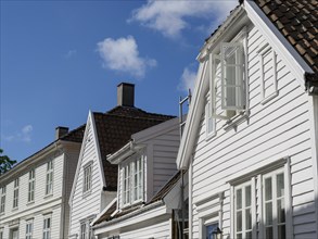 Several white wooden houses with red tiled roofs and open windows under a sunny sky, white wooden