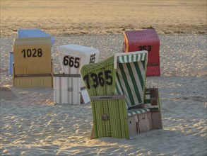 Different coloured beach chairs at sunset on a sandy beach in a quiet atmosphere, sunset on a quiet