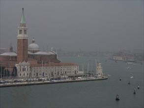 San Giorgio Maggiore church in Venice at foggy dusk, surrounded by water and boats, church towers