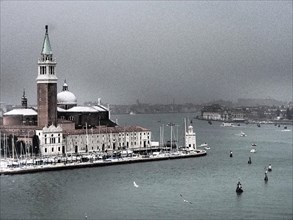 A view of Venice with a church and surrounding boats in the water on a cloudy day, church towers