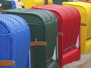 Close-up of colourful beach chairs in different colours arranged on the beach, beach chairs and