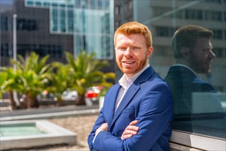 Businessman standing proud with arms crossed outdoors smiling at camera