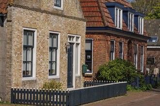 Row of houses with brick facades and white window frames along a quiet street, historic houses and