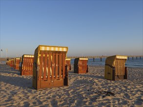 Beach chairs on the sandy beach illuminated by the evening sun, with a view of the sea and the
