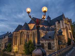 An illuminated gothic cathedral and towers in a park at night, historic buildings with towers and
