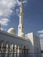 Beautiful mosque with white domes and minarets under a clear blue sky with clouds, large mosque