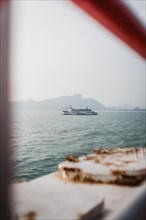 Tranquil sea view of a ferry, framed by parts of a ship. Surat Thani, Thailand, Asia